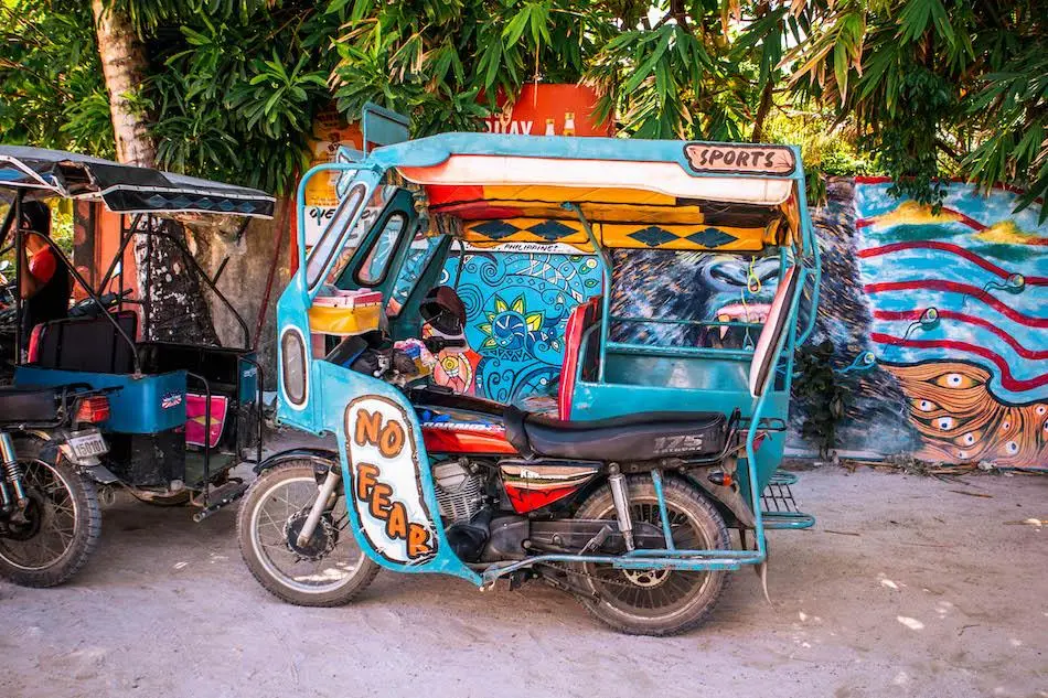 Tricycle with sidecar on a palm-lined road in Siargao, the most common local transport